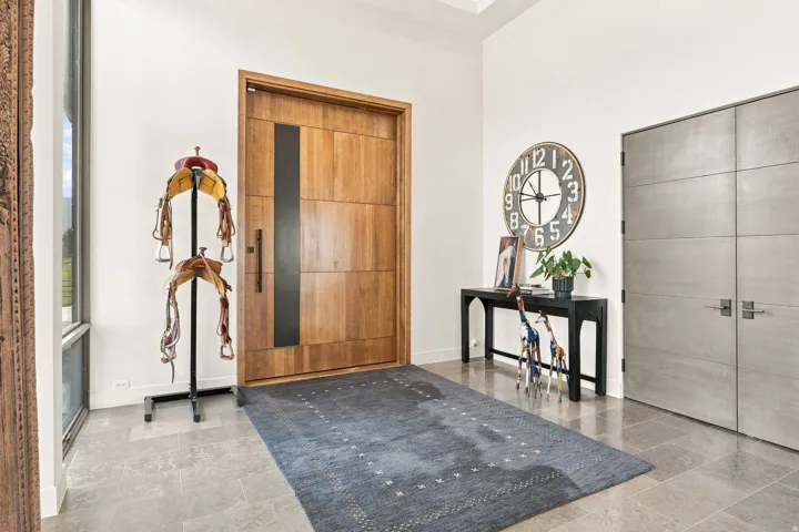 Wood-paneled entry door with vertical glass insert, light gray floor tiling, and light-toned walls