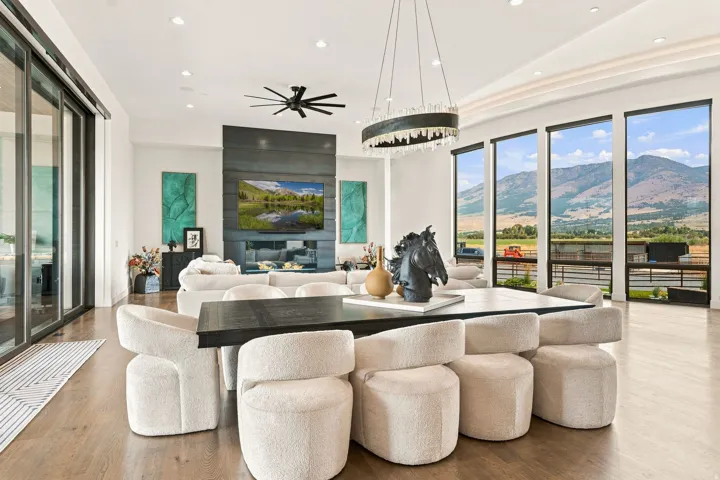 Hardwood flooring throughout, a linear gas fireplace set within a dark-paneled wall, a black ceiling fan, and large sliding glass doors