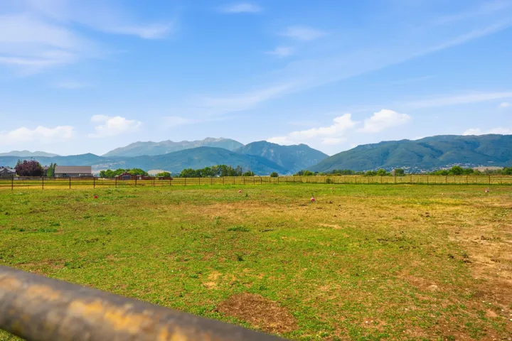 Expansive open acreage featuring a perimeter fence and distant mountain backdrops