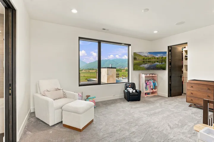 Expansive window with mountain scenery, recessed ceiling lighting, wall-mounted television, built-in closet system, and a sliding pocket door