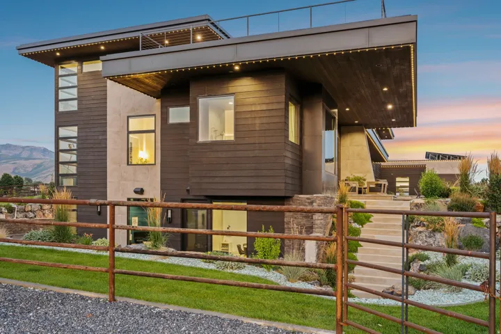 Modern architectural exterior featuring mixed material siding, flat roofline, integrated outdoor lighting, and multi-level landscaping