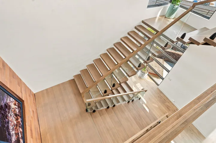 Floating staircase featuring wood treads, glass panel railing, and wood handrail