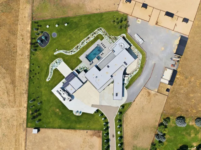 Modern architecture with a flat roof, an in-ground swimming pool, manicured lawns, extensive concrete paving, and a solar panel array