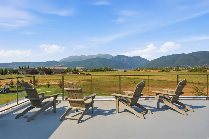 Expansive rooftop deck featuring a level surface, glass panel railing, and scenic mountain range backdrop