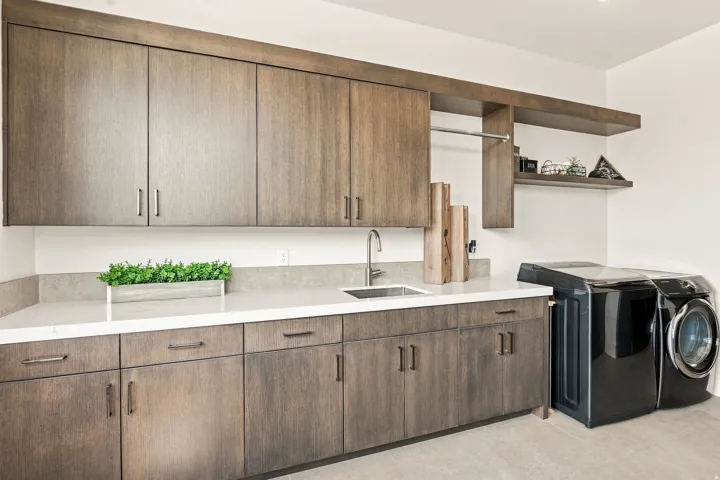 Wood-finish cabinetry with brushed nickel hardware, light-toned countertops, and a stainless steel undermount sink