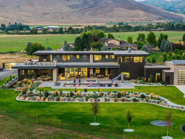 Contemporary multi-level residence featuring expansive windows, a large patio with built-in seating, a swimming pool, and terraced landscaping