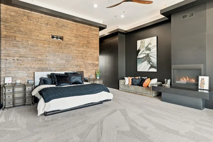 Textured wood-panel accent wall, modern ceiling fan, recessed lighting, carpet flooring, and a built-in fireplace