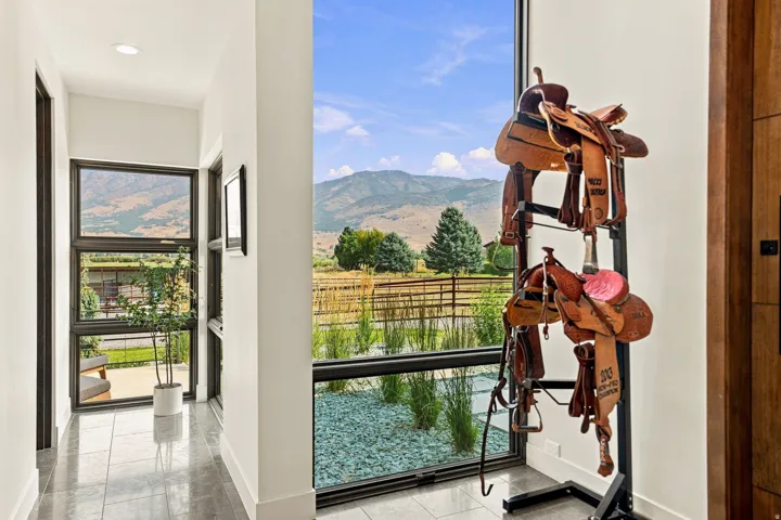 Expansive floor-to-ceiling window system, natural wood door with dark hardware, recessed ceiling lighting, and polished stone tile flooring