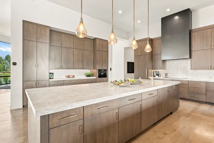 Expansive kitchen island with a light-toned countertop, wood-finish cabinetry, and built-in appliances