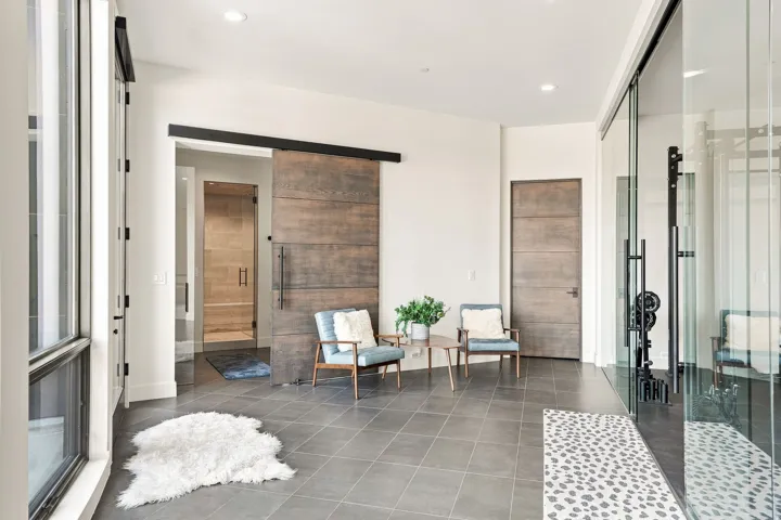 Wood-finish barn door, large format floor tile, recessed lighting, and a glass-enclosed space