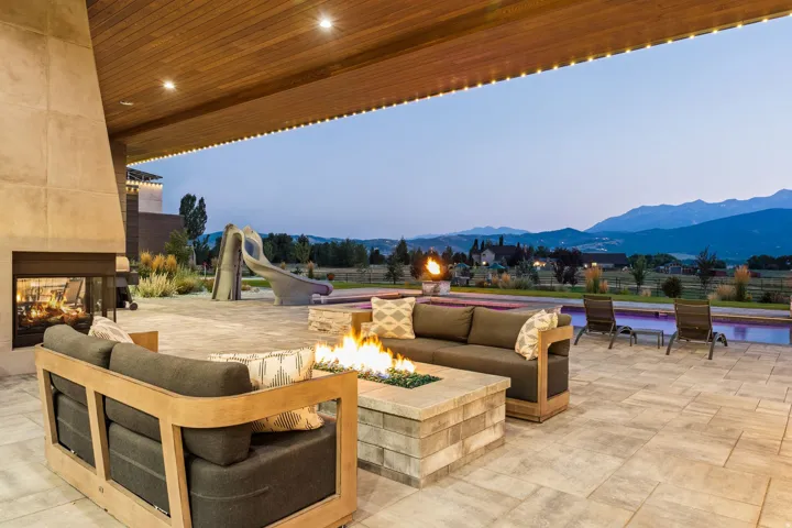 Expansive covered patio featuring a stone fireplace, wood-finish ceiling, and recessed lighting