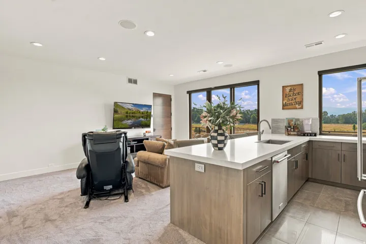 Open-concept living area featuring an island with a built-in sink, stainless steel appliances, and wood-finish cabinetry