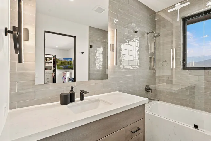 Modern vanity with a light countertop and undermount sink, illuminated by twin vertical light fixtures