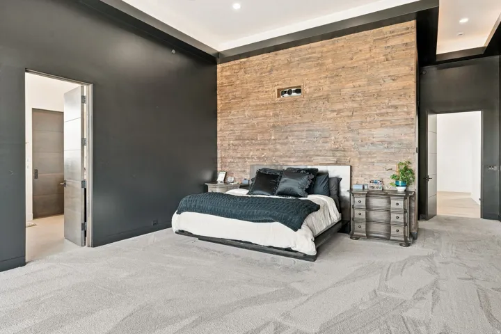Feature wall with stacked stone, recessed lighting, high ceilings, dark accent paint, and light-colored carpeting