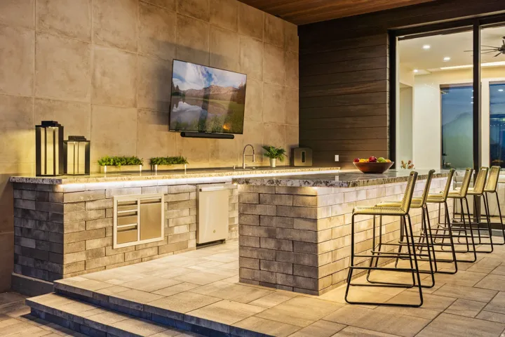 Outdoor kitchen featuring a built-in grill, integrated refrigerator, and a large television
