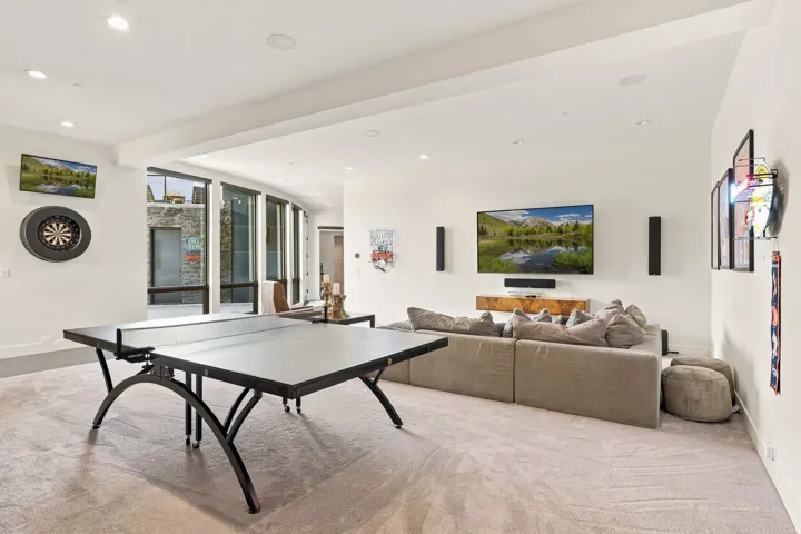 Spacious room with light-colored carpeting, recessed lighting, and a large wall-mounted television