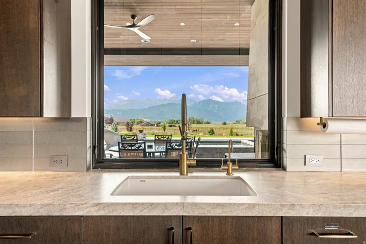 Kitchen featuring a single basin sink with brass-finish faucet, light-toned countertop, and dark wood-finish cabinetry