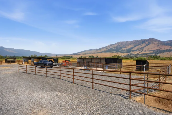 Gravel surface with metal fencing, multiple shelters, and distant mountain scenery
