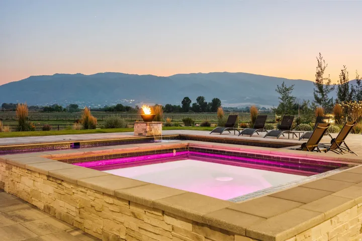 Integrated spa with stone-clad exterior, surrounding hardscaping, and a distinct fire feature
