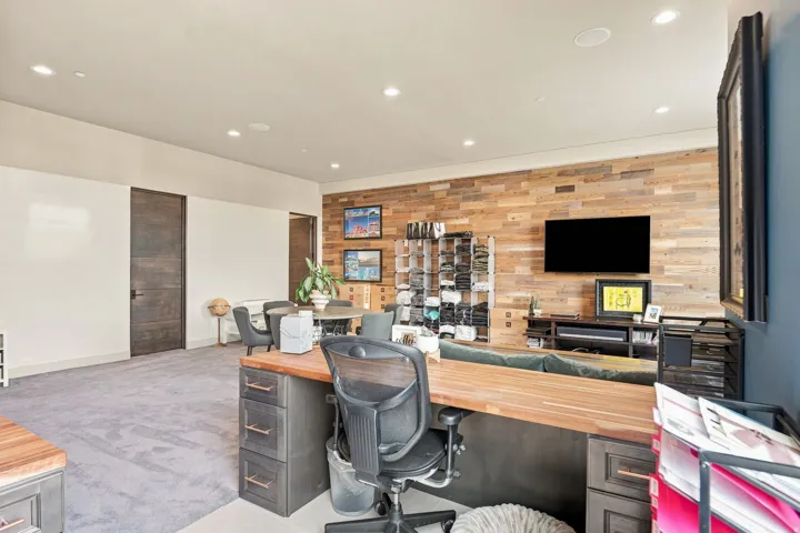 Recessed lighting illuminates the space, featuring a wood-panel accent wall and dark wood-finish doors