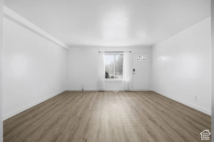 2986 - Open concept living space with wood-finish flooring, white walls, and a white entry door with an arched glass insert