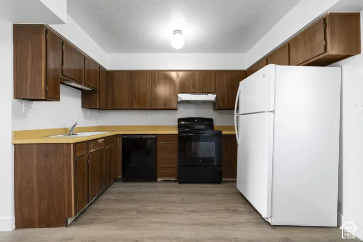 2984 - Kitchen featuring wood-finish cabinetry, light-toned countertops, and wood-finish flooring