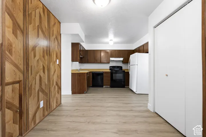 2984 - Wood-finish flooring, wood-paneled accent wall, wood cabinetry, built-in kitchen appliances, and overhead lighting