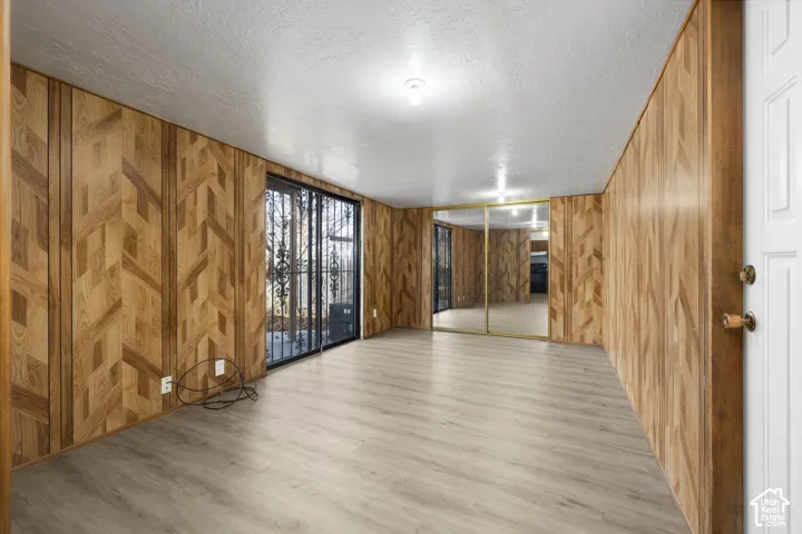 2984 - Light wood-finish flooring, full-wall wood paneling, sliding glass doors, built-in mirrored closet doors, and recessed ceiling lighting