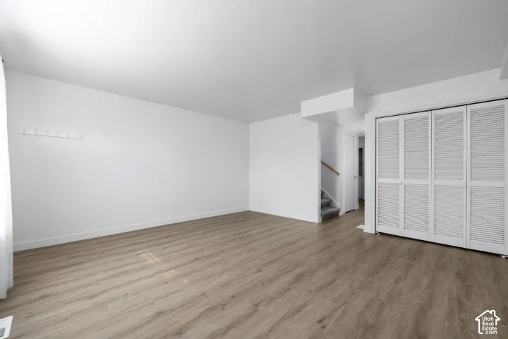 2986 - Wood-finish flooring throughout, white walls, louvered bi-fold closet doors, and staircase with carpeted treads