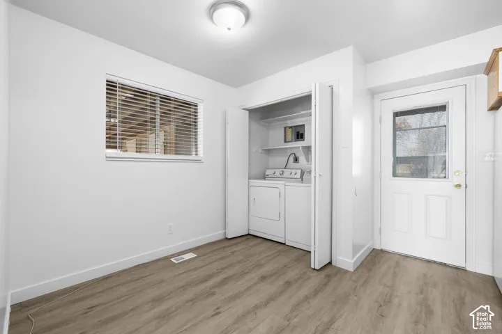 2986 - Wood-finish flooring, white walls, built-in laundry area with appliances, ceiling-mounted light fixture, and an exterior door with a glass insert