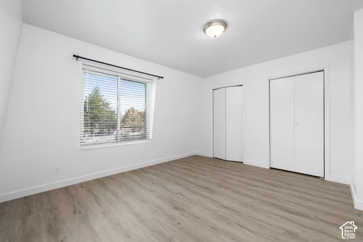 2986 - Wood-finish flooring with white walls, dual bi-fold closet doors, and a flush mount ceiling light fixture