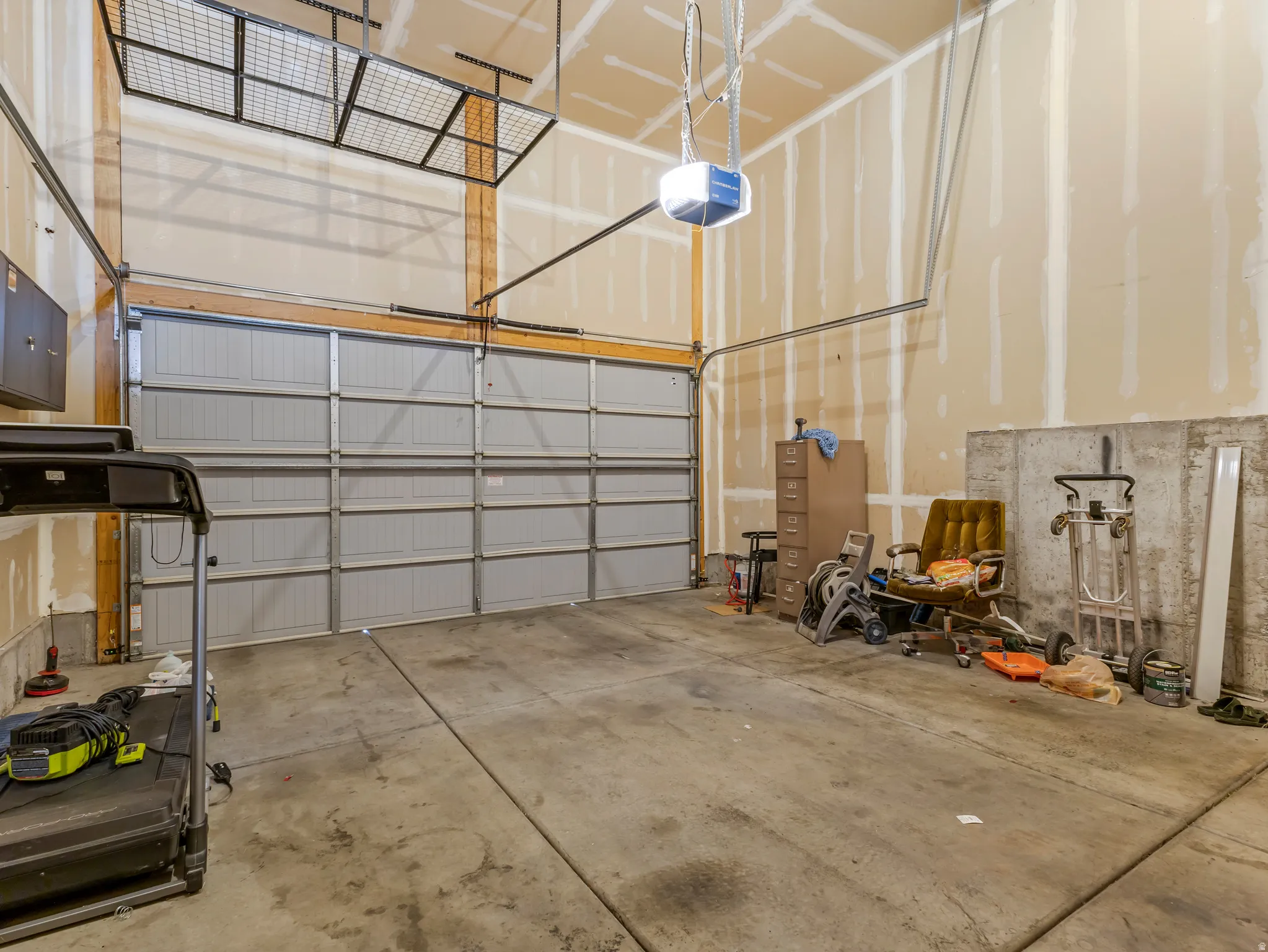 Attached garage with a sectional garage door, concrete flooring, and an overhead storage rack