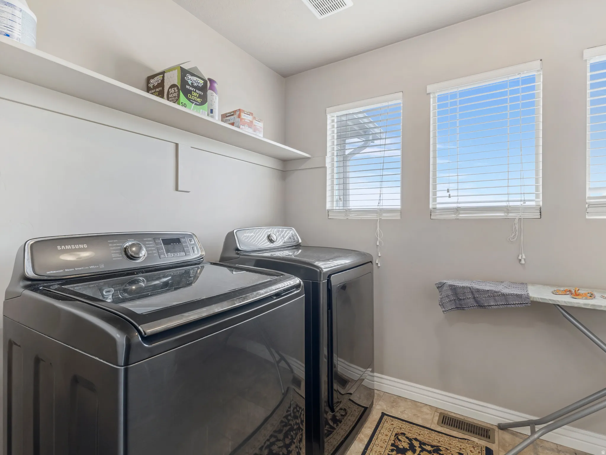Laundry area featuring a built-in shelf, multiple windows, and tile flooring