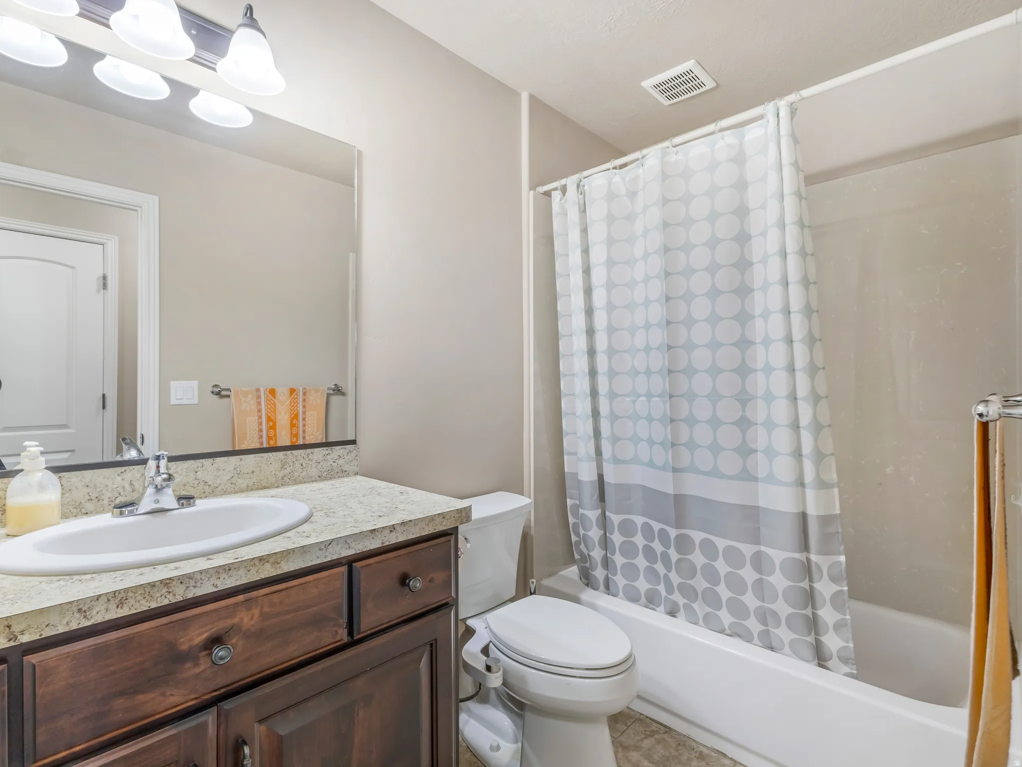 Bathroom featuring a vanity with a light-colored countertop, an integrated sink, a wood-finish cabinet, and a shower-bathtub combination