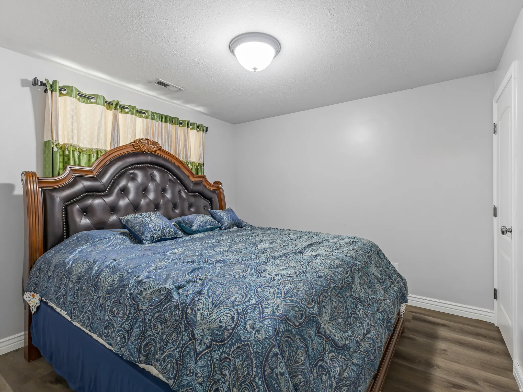 Wood-finish flooring, white trim, and a white interior door with a dark knob