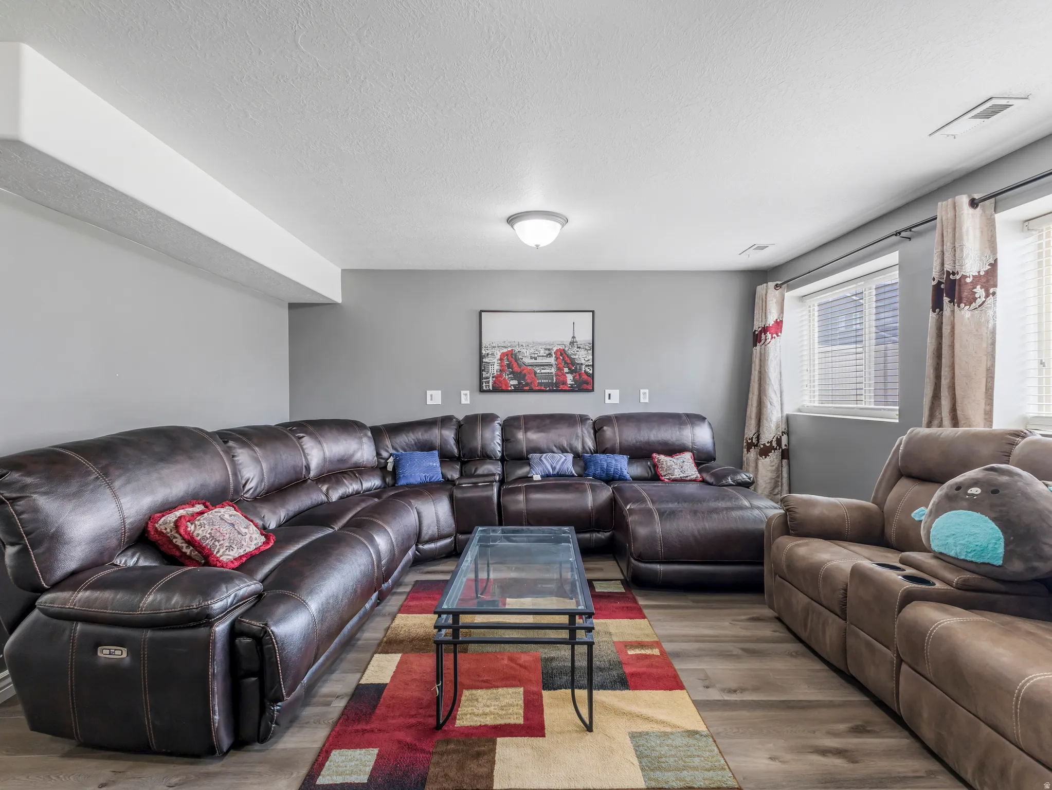 Recessed ceiling beam, two windows with blinds, flush mount ceiling light, and wood-finish flooring