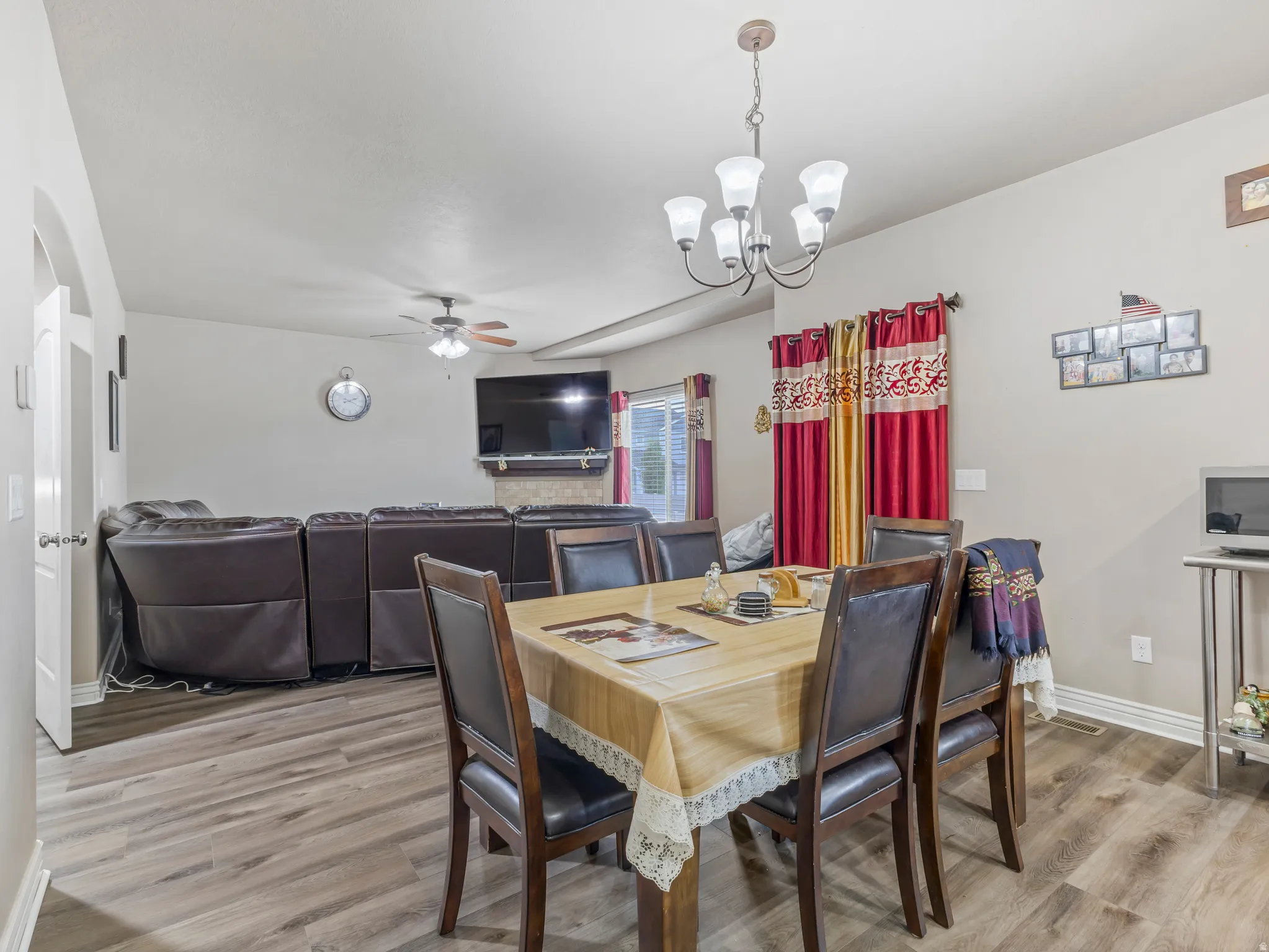 Open-concept living space with wood-finish flooring, a contemporary ceiling fan, and a chandelier-style light fixture