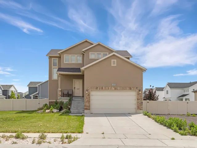 Two-story stucco exterior featuring stacked stone accents, an attached two-car garage, and a covered front entry