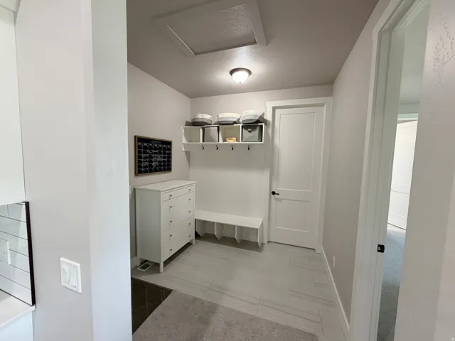 Mudroom featuring built-in bench, storage cubbies, wall hooks, and tile flooring