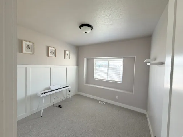 Board and batten wall detailing, recessed window, window blinds, flush mount ceiling light, and carpeted flooring