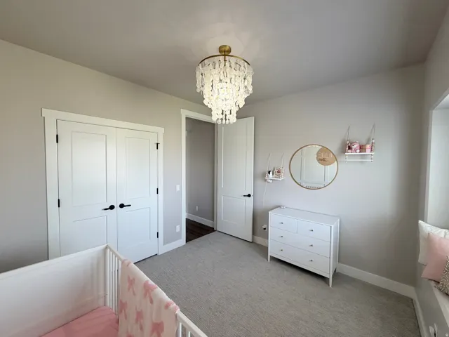 Textured carpeting, contemporary ceiling light fixture, double-panel closet doors with dark hardware, recessed window area, and neutral wall tones