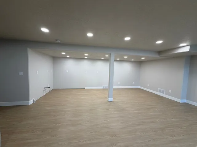 Expansive open-concept room featuring light wood-finish flooring, recessed lighting, and neutral wall tones