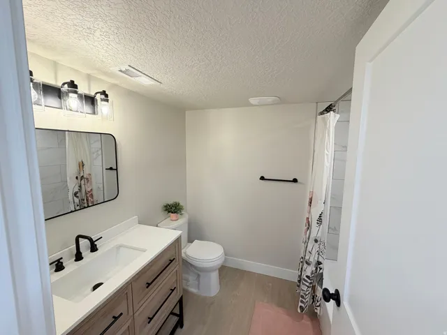 Bathroom featuring a wood-finish vanity with a white countertop, rectangular sink, and matte black faucet