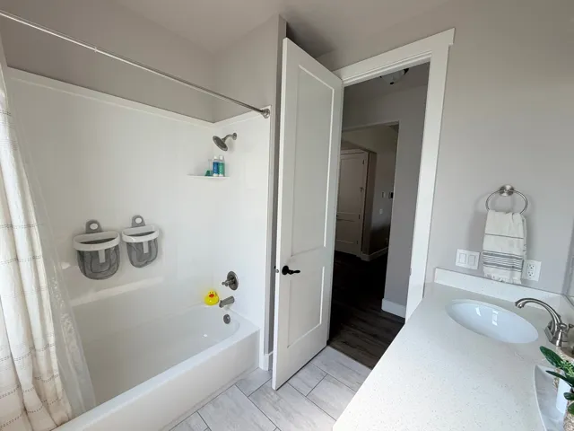 White fiberglass tub and shower combination with an integrated shelf