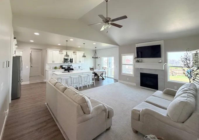 Vaulted ceiling, recessed lighting, white shaker cabinetry, kitchen island with seating, and a fireplace with tile surround