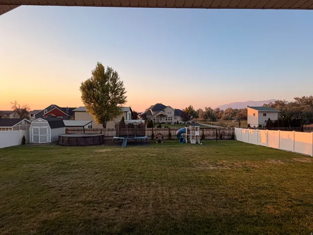 Expansive grassy yard with a white privacy fence