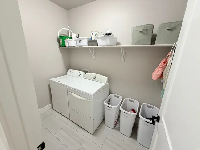 Laundry area featuring tile flooring, a built-in shelf, and a clothing rod