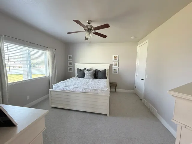 Window with horizontal blinds, ceiling fan with integrated lighting, light gray wall paint, and gray carpet flooring