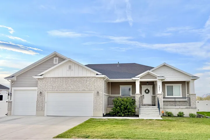 Exterior featuring a partial brick facade, dual garage doors, a covered front porch, and a paved driveway
