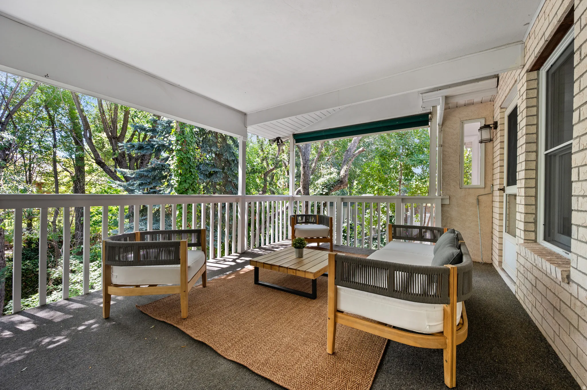 The expansive covered porch creates a wonderful outdoor living space surrounded by mature trees.